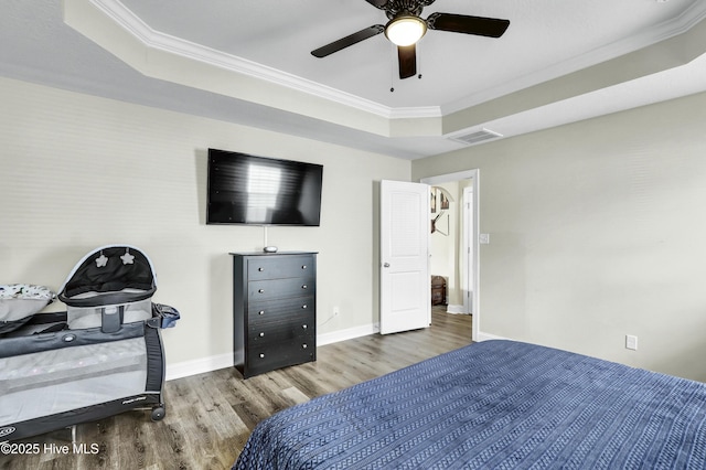 bedroom featuring baseboards, crown molding, a tray ceiling, and wood finished floors