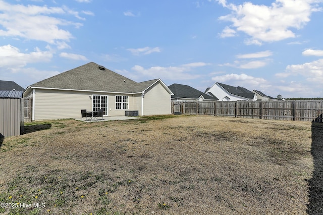 rear view of house featuring a patio, a yard, a fenced backyard, and roof with shingles