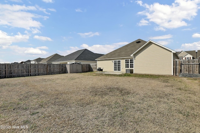 back of property featuring a storage unit, an outbuilding, a fenced backyard, and a yard