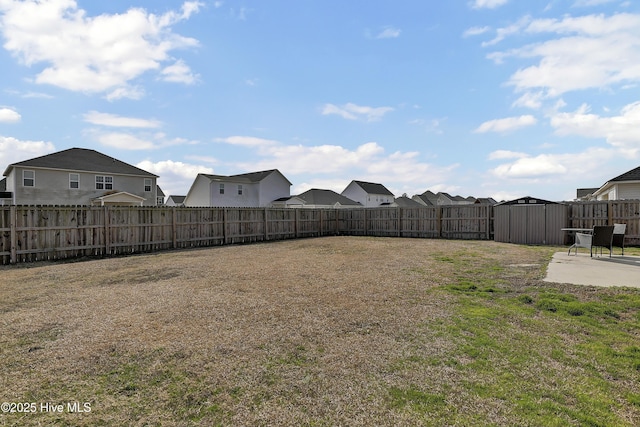 view of yard featuring a storage unit, an outbuilding, a patio, a fenced backyard, and a residential view