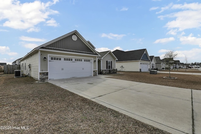 view of front of property featuring driveway, stone siding, board and batten siding, an attached garage, and central AC unit