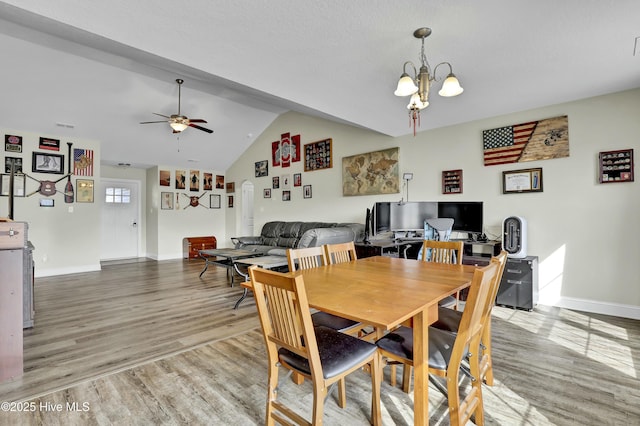 dining room with vaulted ceiling, ceiling fan with notable chandelier, baseboards, and wood finished floors