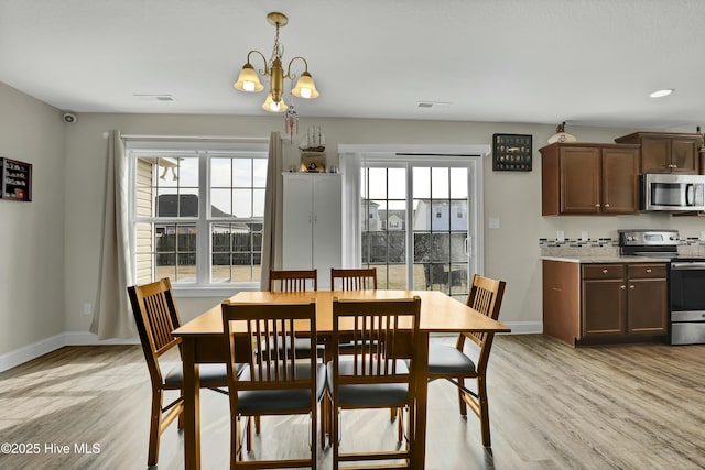 dining area featuring a healthy amount of sunlight, visible vents, and light wood finished floors