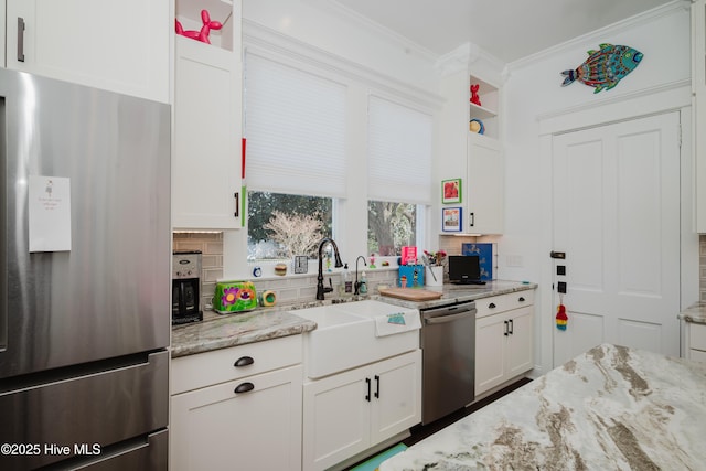 kitchen with ornamental molding, a sink, light stone counters, white cabinetry, and stainless steel appliances