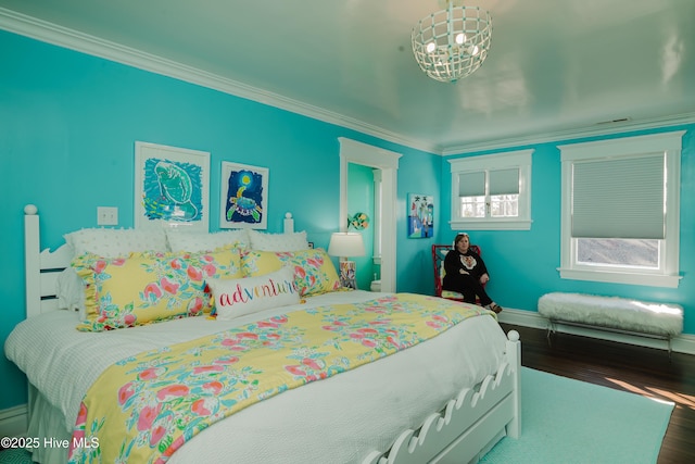 bedroom with an inviting chandelier, crown molding, baseboards, and wood finished floors