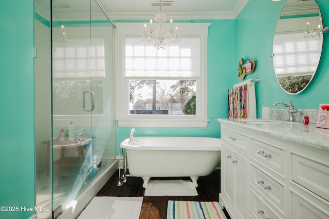 bathroom with vanity, wood finished floors, a stall shower, a freestanding bath, and ornamental molding