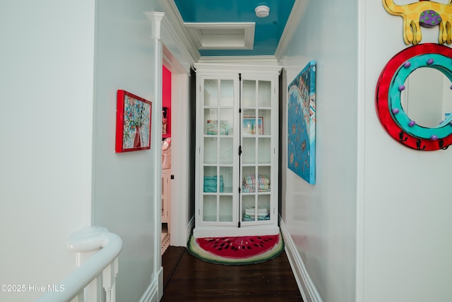 interior space with attic access, wood finished floors, baseboards, and ornamental molding