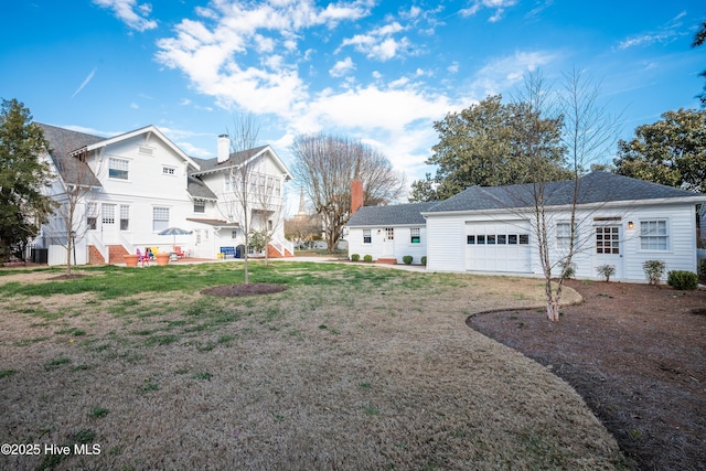 back of property with a garage, a lawn, and a chimney