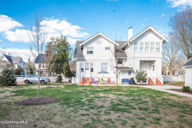 view of front of home featuring entry steps, a chimney, a front lawn, and fence