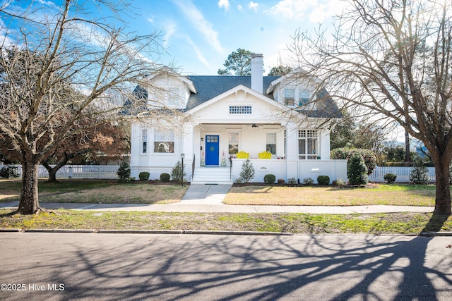 view of front of house featuring a fenced front yard, covered porch, a chimney, and a front yard