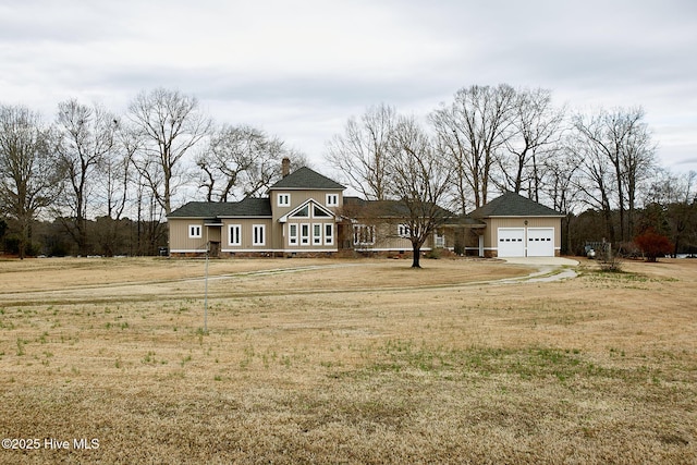 view of front of home featuring a front lawn, an attached garage, driveway, and a chimney