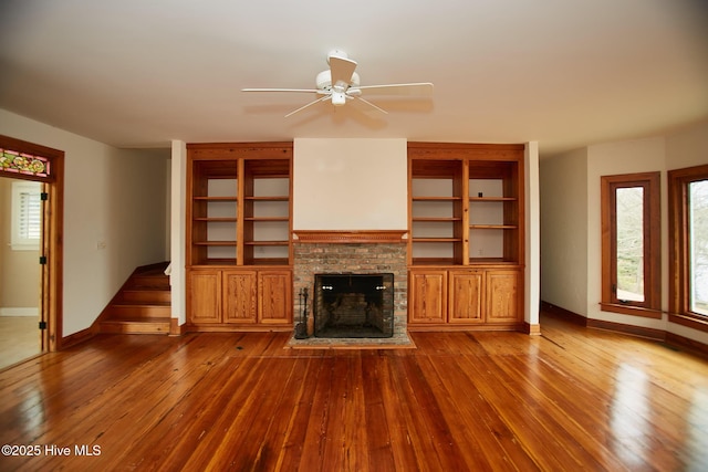 unfurnished living room featuring ceiling fan, baseboards, hardwood / wood-style floors, and a fireplace