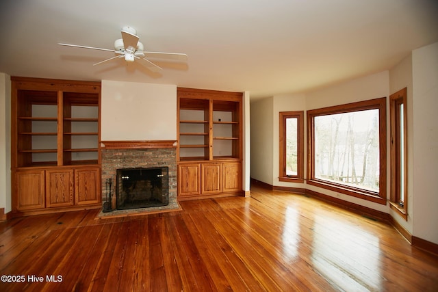 unfurnished living room featuring hardwood / wood-style flooring, a fireplace, baseboards, and ceiling fan