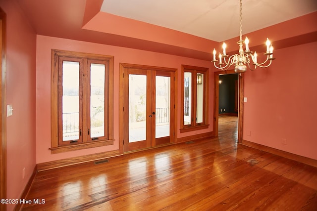 spare room featuring a tray ceiling, baseboards, hardwood / wood-style floors, and french doors