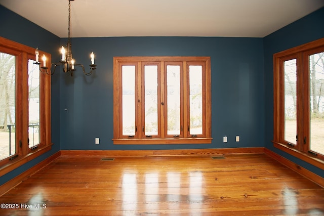 unfurnished room featuring plenty of natural light, baseboards, and wood-type flooring