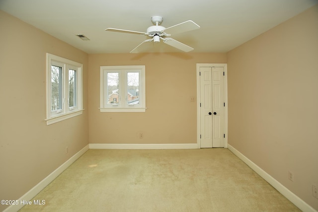 empty room with visible vents, baseboards, light colored carpet, and ceiling fan