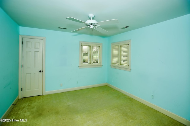 carpeted empty room with a ceiling fan, visible vents, and baseboards