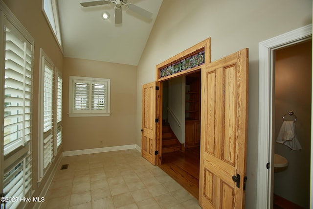 interior space featuring light tile patterned floors, a ceiling fan, baseboards, visible vents, and lofted ceiling