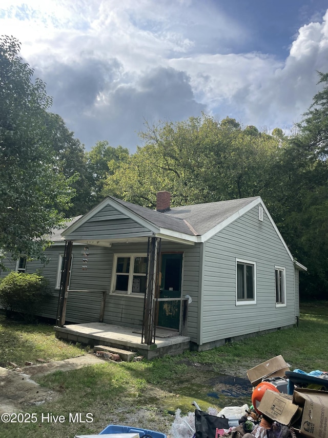 view of front facade with covered porch and a chimney