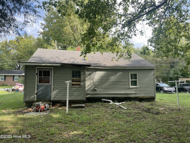 rear view of house featuring a yard and a chimney