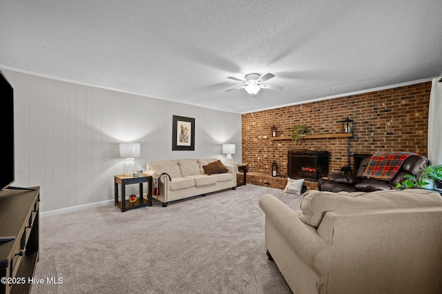 carpeted living room featuring brick wall, a fireplace, ceiling fan, ornamental molding, and a textured ceiling