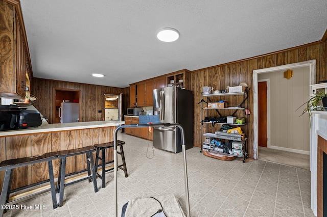 kitchen featuring light floors, wooden walls, appliances with stainless steel finishes, and a fireplace