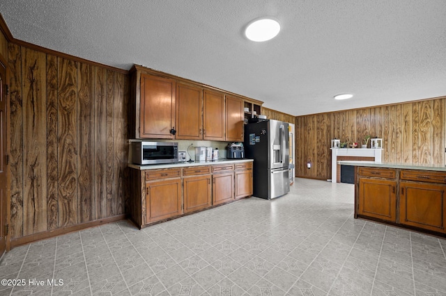 kitchen featuring wood walls, light floors, light countertops, brown cabinets, and stainless steel appliances