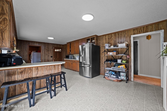 kitchen with light floors, appliances with stainless steel finishes, wood walls, and light countertops