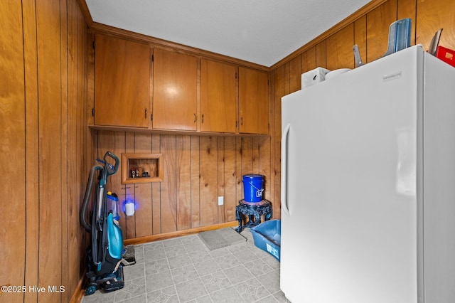 laundry area featuring wooden walls, baseboards, light floors, hookup for a washing machine, and cabinet space