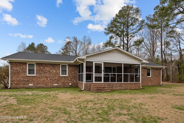 rear view of house with crawl space, a yard, brick siding, and a sunroom