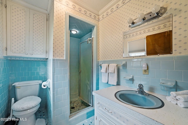 bathroom featuring vanity, wainscoting, a shower stall, and wallpapered walls