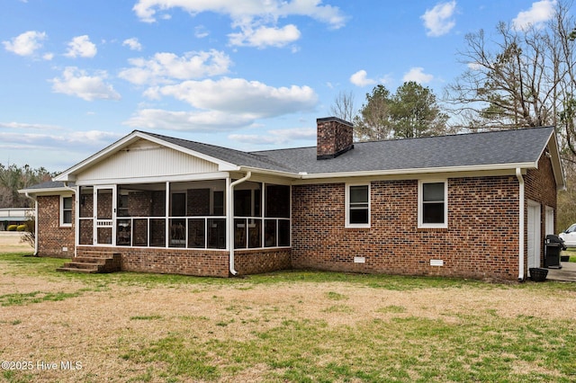 rear view of house featuring a sunroom, a chimney, crawl space, a lawn, and brick siding