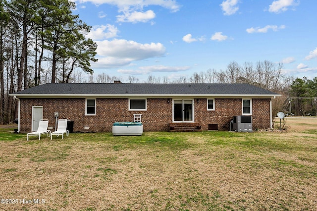 back of house with entry steps, a lawn, brick siding, and crawl space