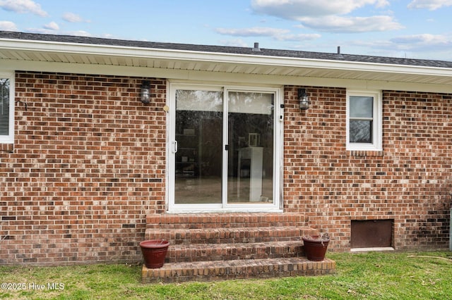 doorway to property featuring brick siding and crawl space