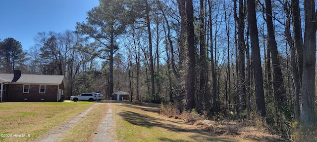 view of street with driveway and a view of trees