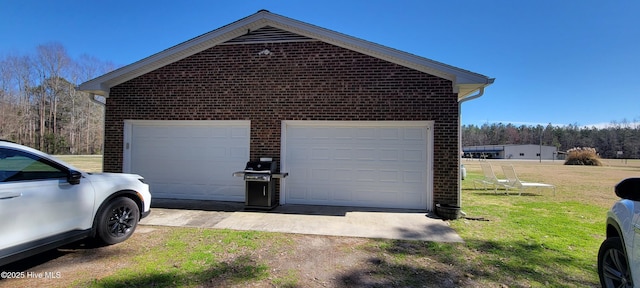 view of property exterior with brick siding, a yard, an outbuilding, and a garage