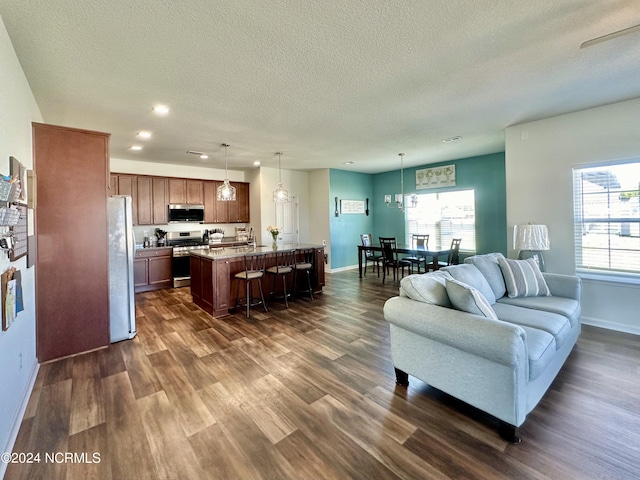 living room with dark wood finished floors, plenty of natural light, baseboards, and a textured ceiling