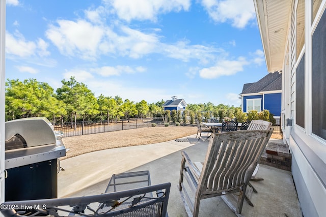 view of patio with outdoor dining space, fence, and a grill