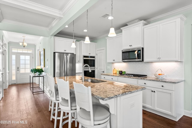 kitchen with dark wood-style floors, a center island with sink, appliances with stainless steel finishes, and a sink