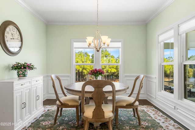 dining space featuring dark wood-style floors, a wainscoted wall, an inviting chandelier, and ornamental molding