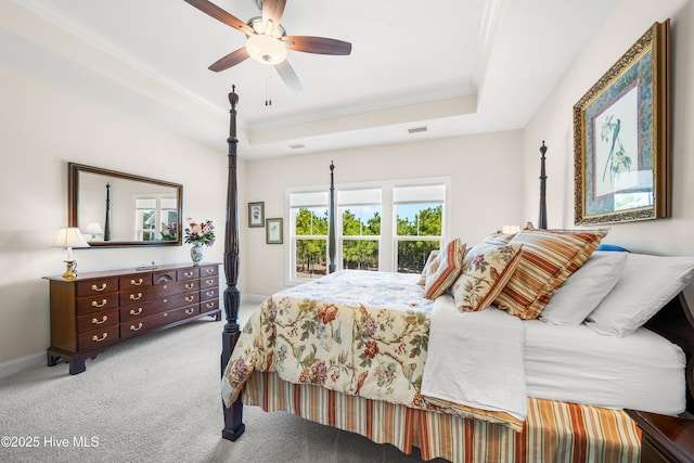 carpeted bedroom featuring visible vents, ornamental molding, baseboards, a raised ceiling, and ceiling fan