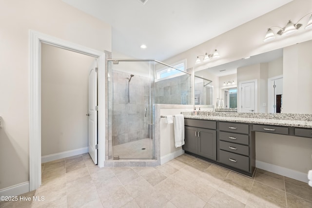 full bath with vanity, baseboards, and a stall shower