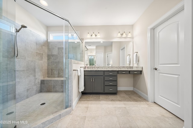 bathroom with tile patterned floors, a shower stall, vanity, and baseboards