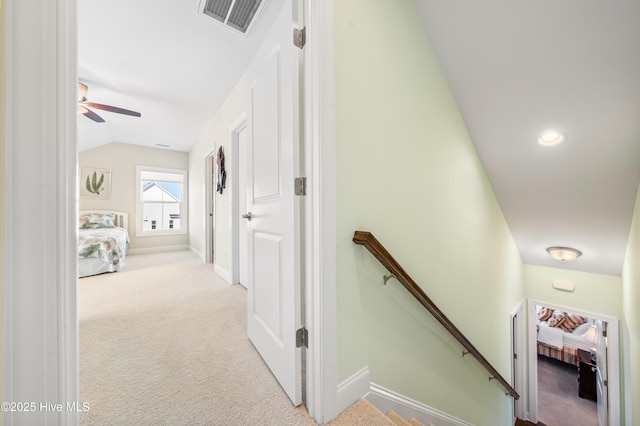 hallway with visible vents, carpet floors, baseboards, vaulted ceiling, and an upstairs landing