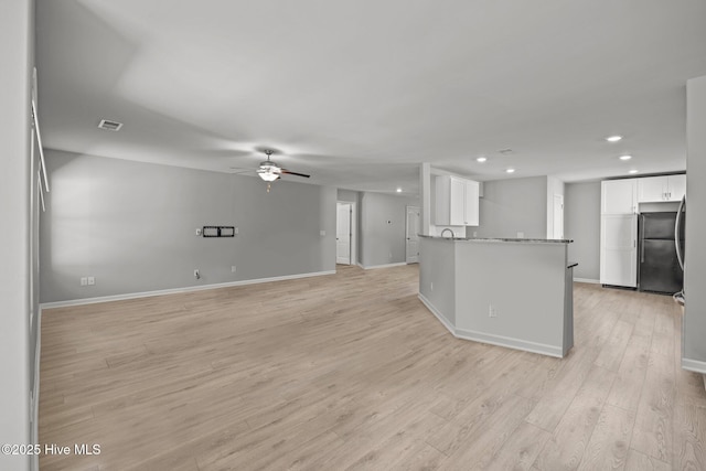 kitchen with a ceiling fan, light wood-style flooring, freestanding refrigerator, and white cabinetry