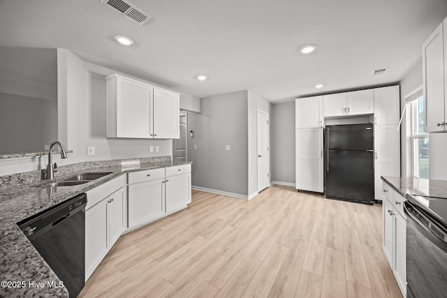 kitchen with visible vents, light stone countertops, light wood-type flooring, black appliances, and a sink