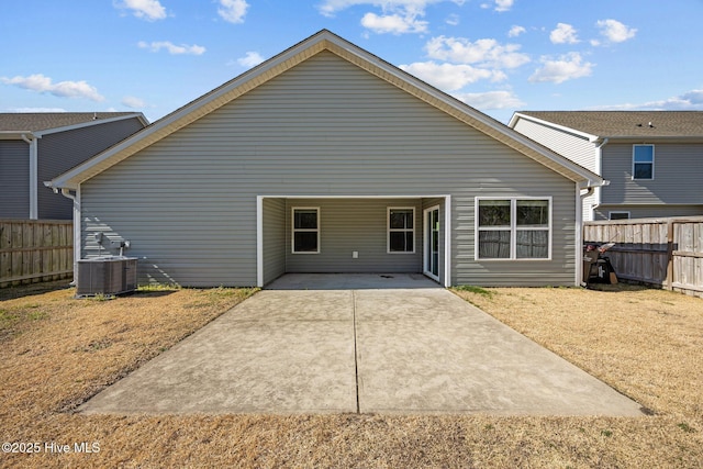 back of house with an attached carport, concrete driveway, central AC, and fence