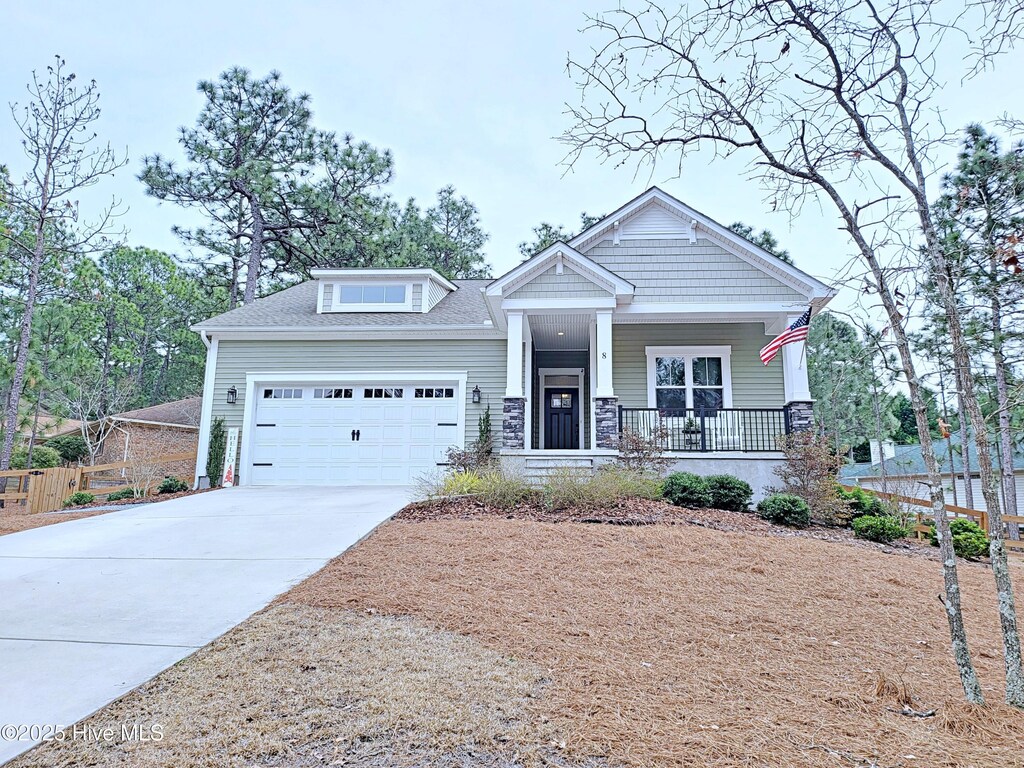 craftsman-style house with concrete driveway, a garage, fence, and covered porch