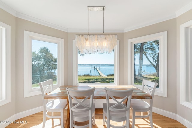 dining room with light wood finished floors, baseboards, a water view, and a wealth of natural light