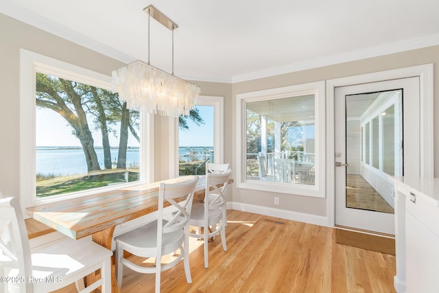 dining room featuring a wealth of natural light, light wood-type flooring, a chandelier, and crown molding